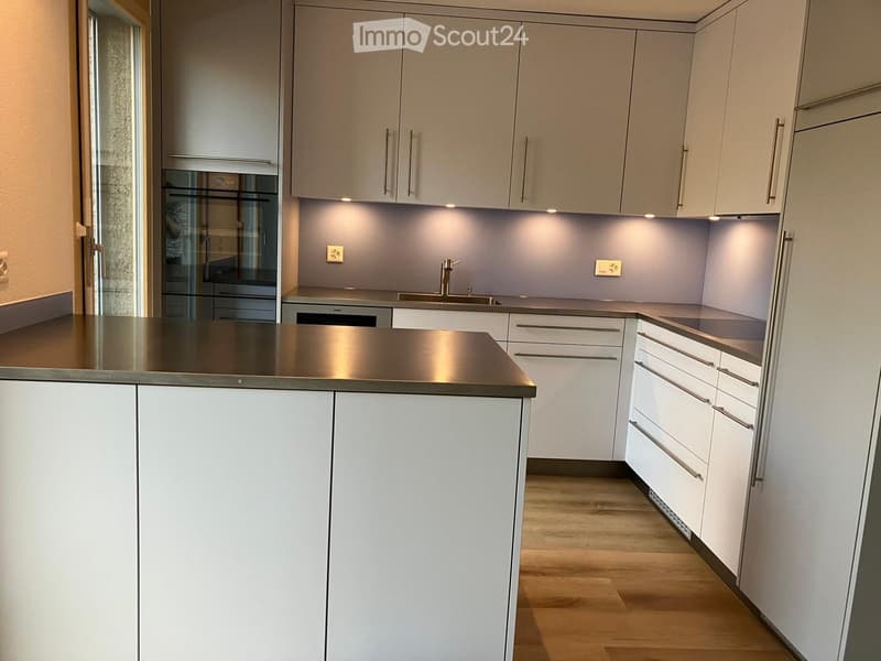 Modern kitchen with white cabinets, stainless steel countertop, and a sink with a faucet.