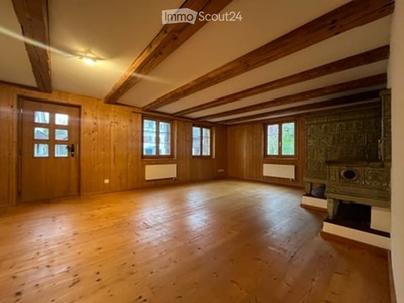 Empty room with wooden walls, wooden floor, large windows, and exposed wooden beams on the ceiling. No furniture or equipment present.