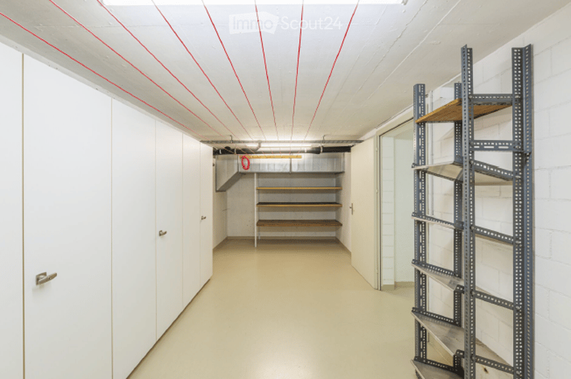 Empty storage room with white walls, wooden shelving, and metal shelving units. No furniture or equipment present.
