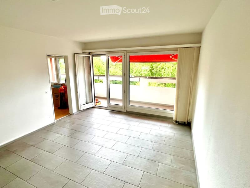 Empty room with tiled floor, large sliding glass doors leading to a balcony, and a mirror on the wall.