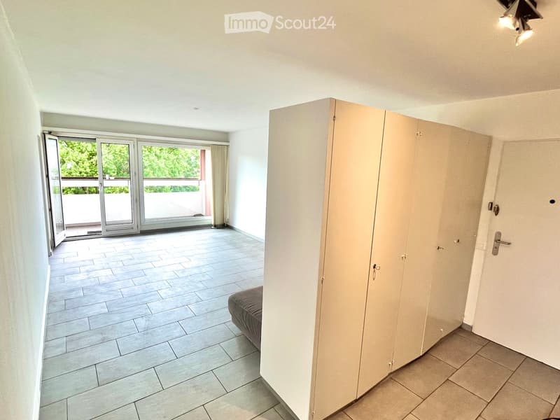 Empty room with tiled flooring, large sliding glass doors leading to a balcony, and built-in closet with mirrored doors.