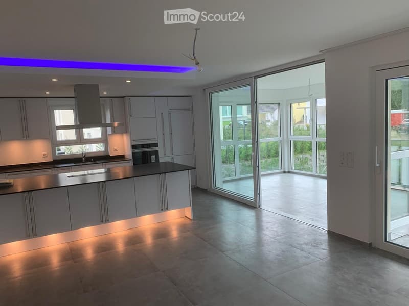 Modern kitchen with white cabinetry, a central island, and large windows leading to an outdoor area.