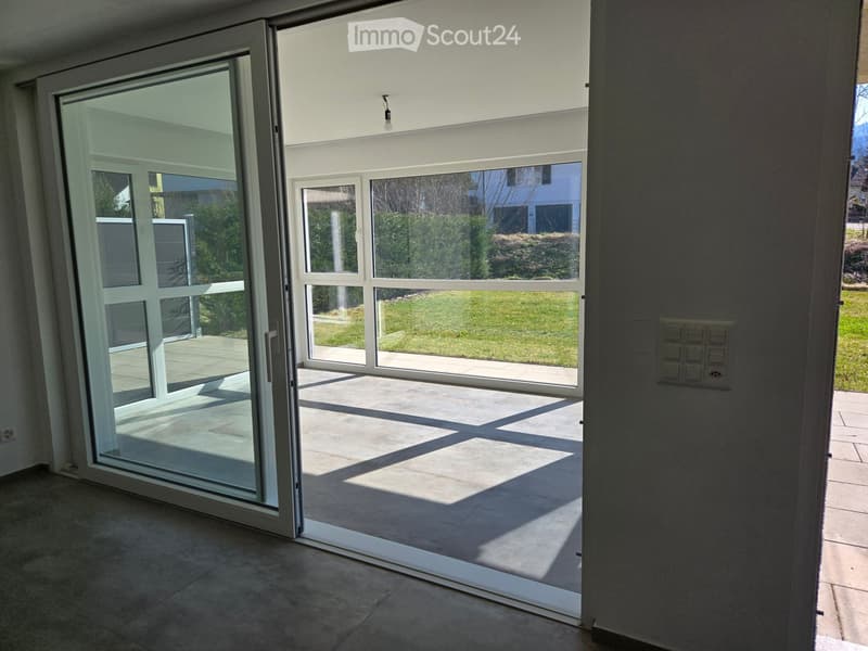 Empty room with large sliding glass doors leading to a patio area, tiled floor, and modern light fixture.