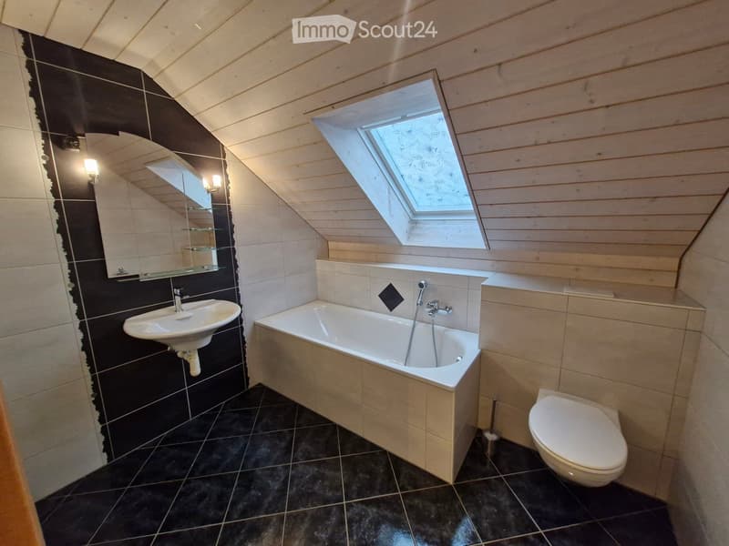 Modern bathroom with black and white tiles, a bathtub, sink, toilet, and a skylight window.
