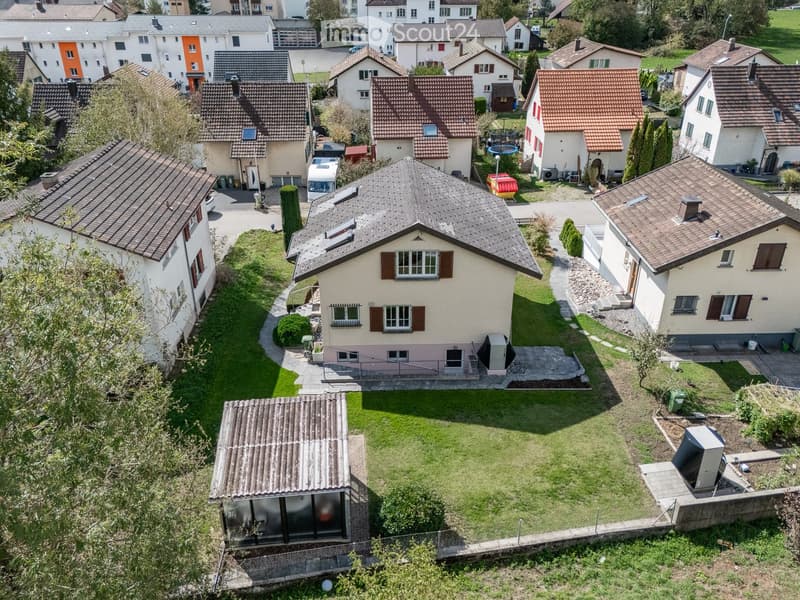 Aerial view of a residential neighborhood with multiple houses, gardens, and driveways.