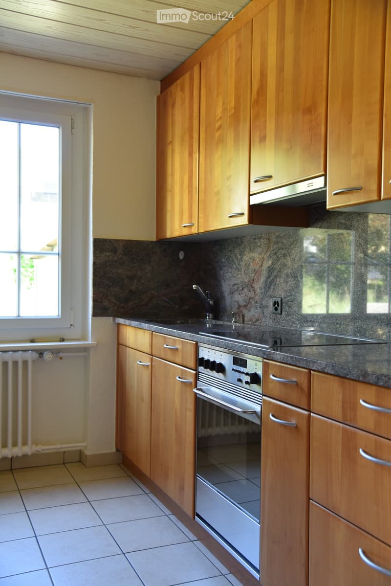 Modern kitchen with wooden cabinets, granite countertop, stainless steel oven, and sink.