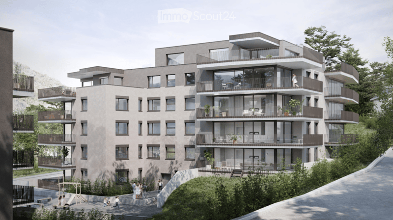 Modern apartment building with multiple balconies, glass walls, and a green area