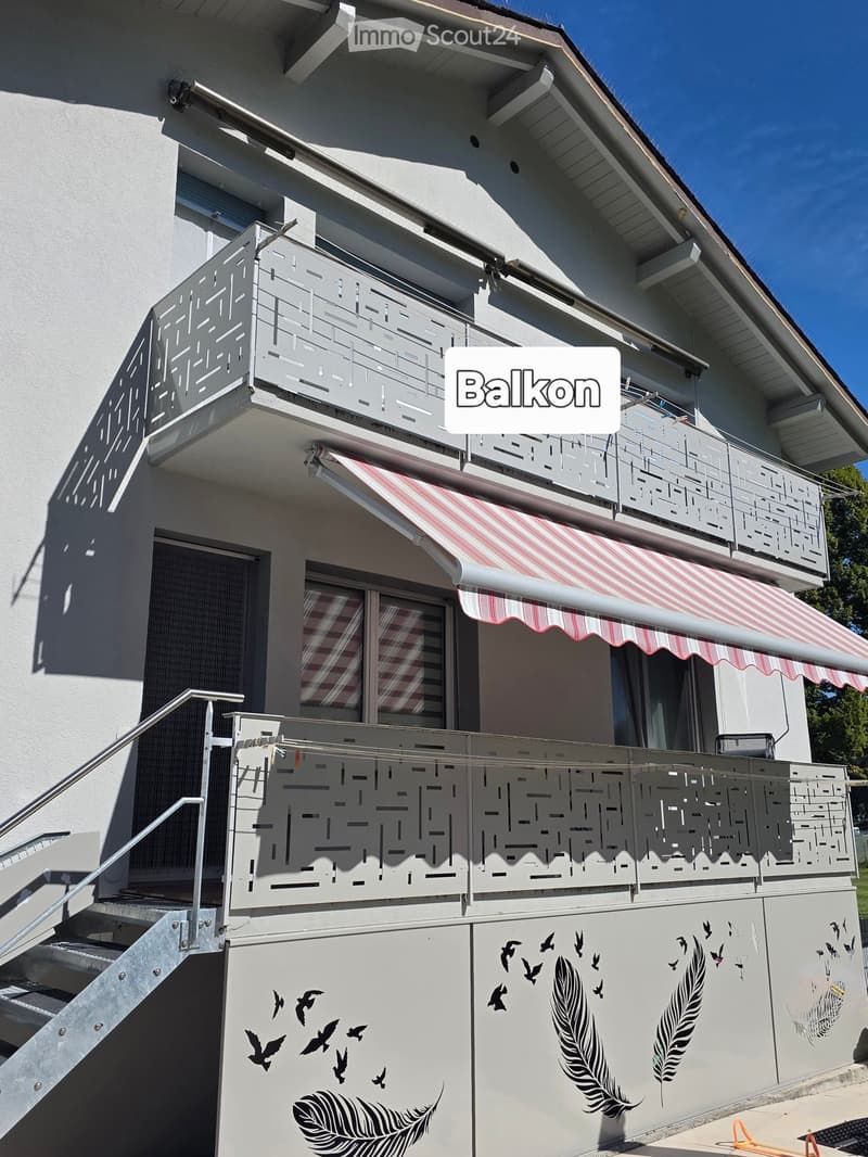 Balcony with decorative metal railing, striped awning, and bird and leaf decals on the wall.
