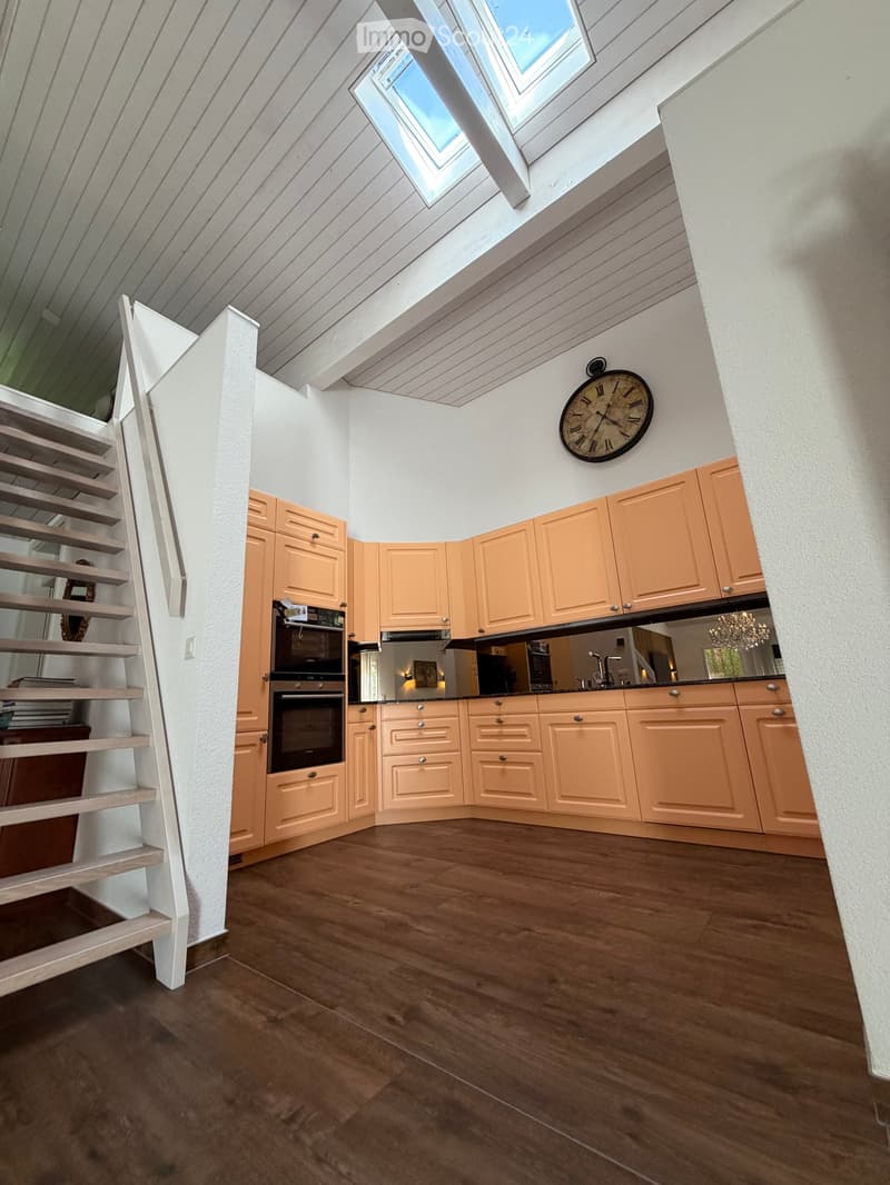 Bright kitchen with light wood cabinets, stainless steel appliances, wooden flooring, and a skylight window above the sink area.