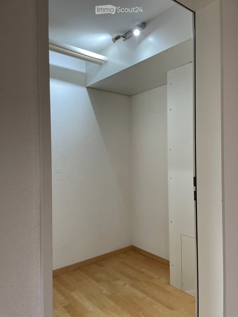 Empty room with wooden flooring, white walls, and a built-in closet with a sliding door.