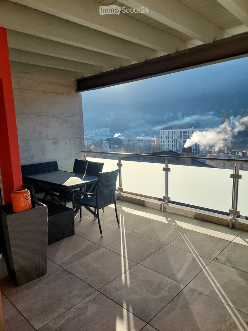 Balcony with tiled floor, metal railing, and a view of the cityscape. Includes a table, chairs, and a decorative vase.