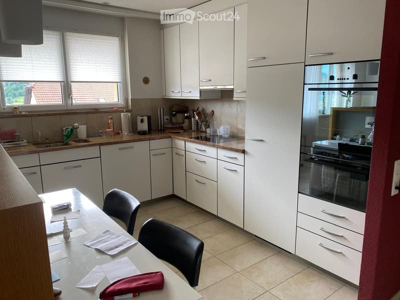 Modern kitchen with white cabinets, stainless steel appliances, and a central island with a table and chairs.