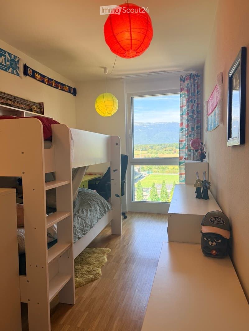 Cozy bedroom with a bunk bed, desk, chair, and large window overlooking a scenic view.