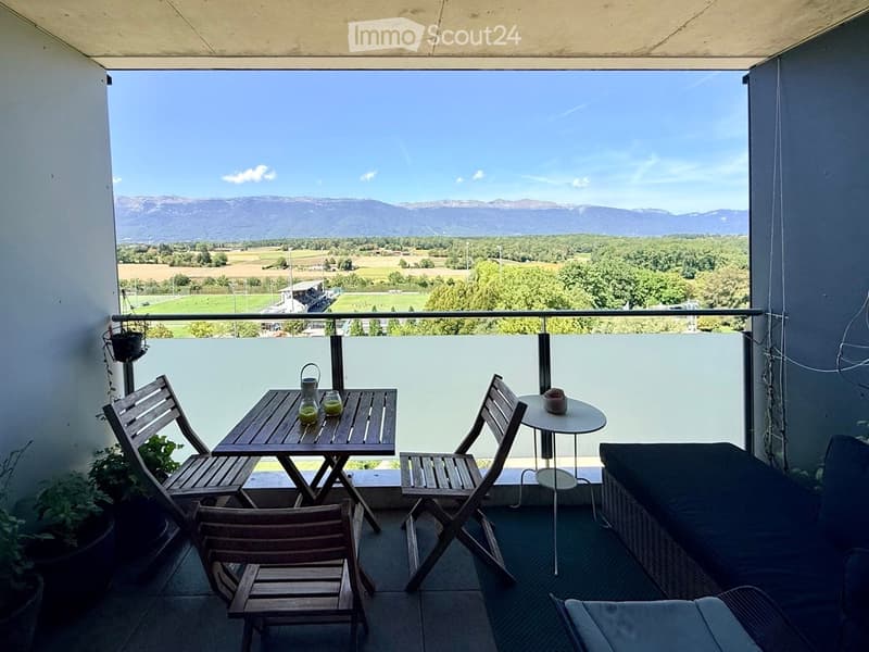 Balcony with a scenic mountain view, featuring a small wooden table, chairs, a sofa, and a round side table.