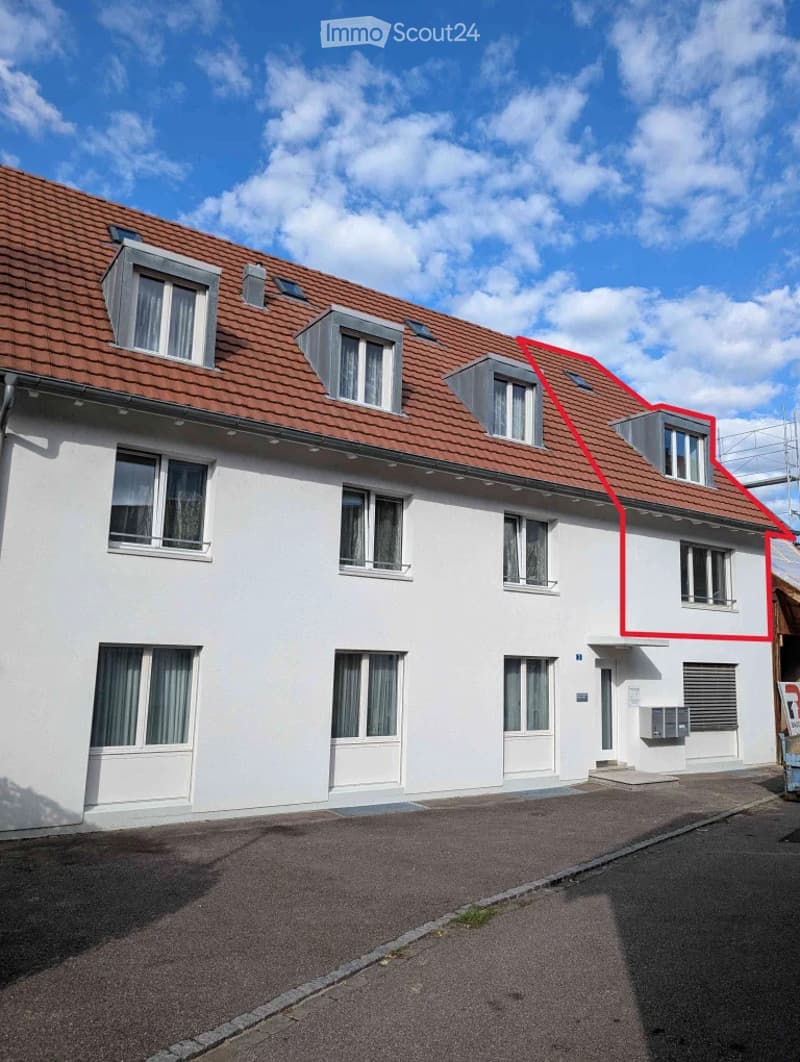 Two-story residential building with white walls, red-tiled roof, multiple windows, and a small balcony on the upper floor.