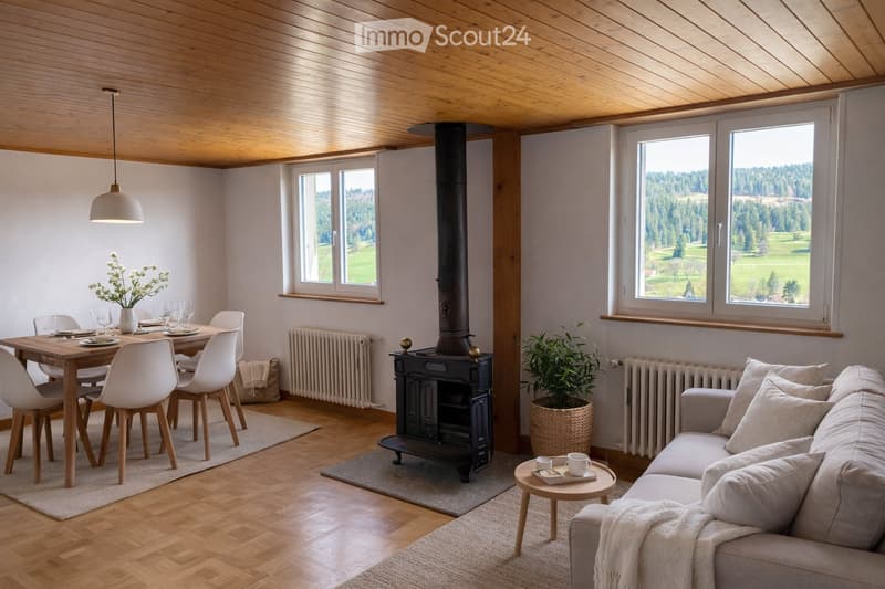 Bright living and dining area with wooden floors, exposed wooden ceiling, large windows offering scenic views, a fireplace, a sofa, a coffee table, a dining table with chairs, and a flower vase on the table.