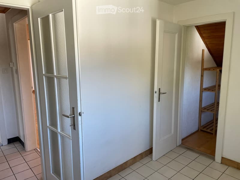 Empty hallway with tiled floor, white walls, and several open doors leading to other rooms.