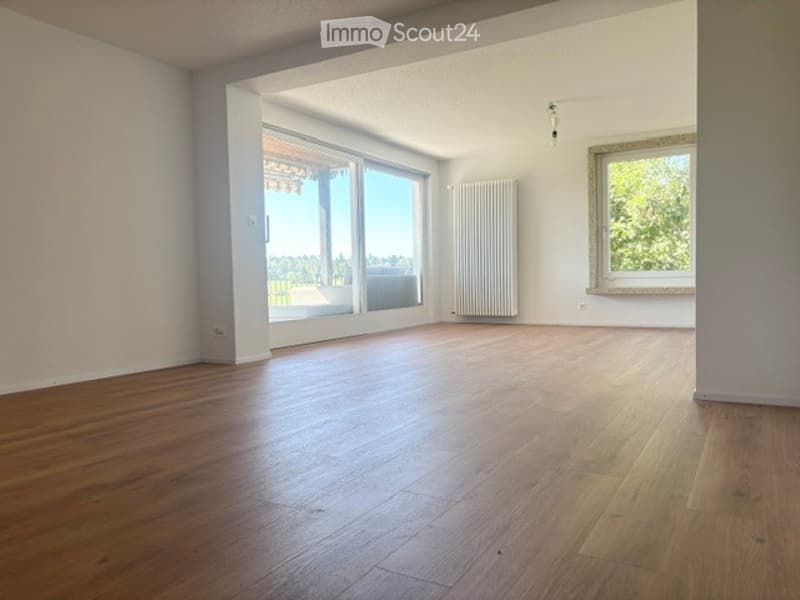 Bright, empty room with wooden flooring, large windows, and radiators. No furniture or equipment present.