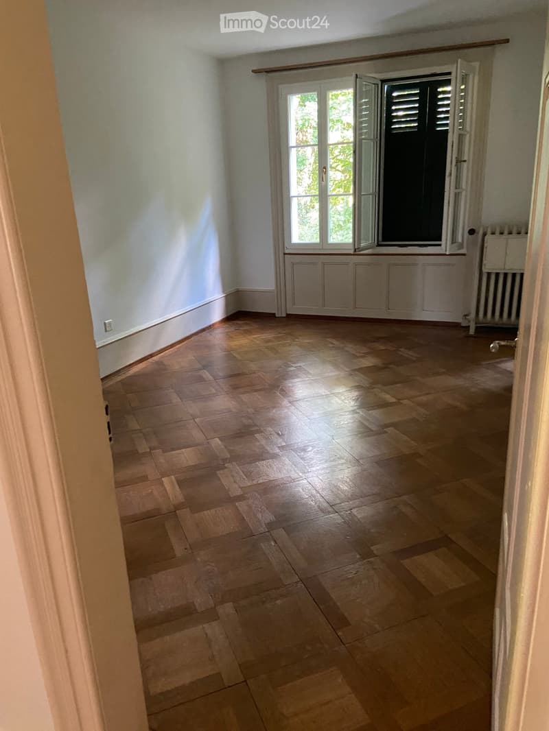 Empty room with wooden flooring, white walls, and a window with shutters. No furniture or equipment is present.