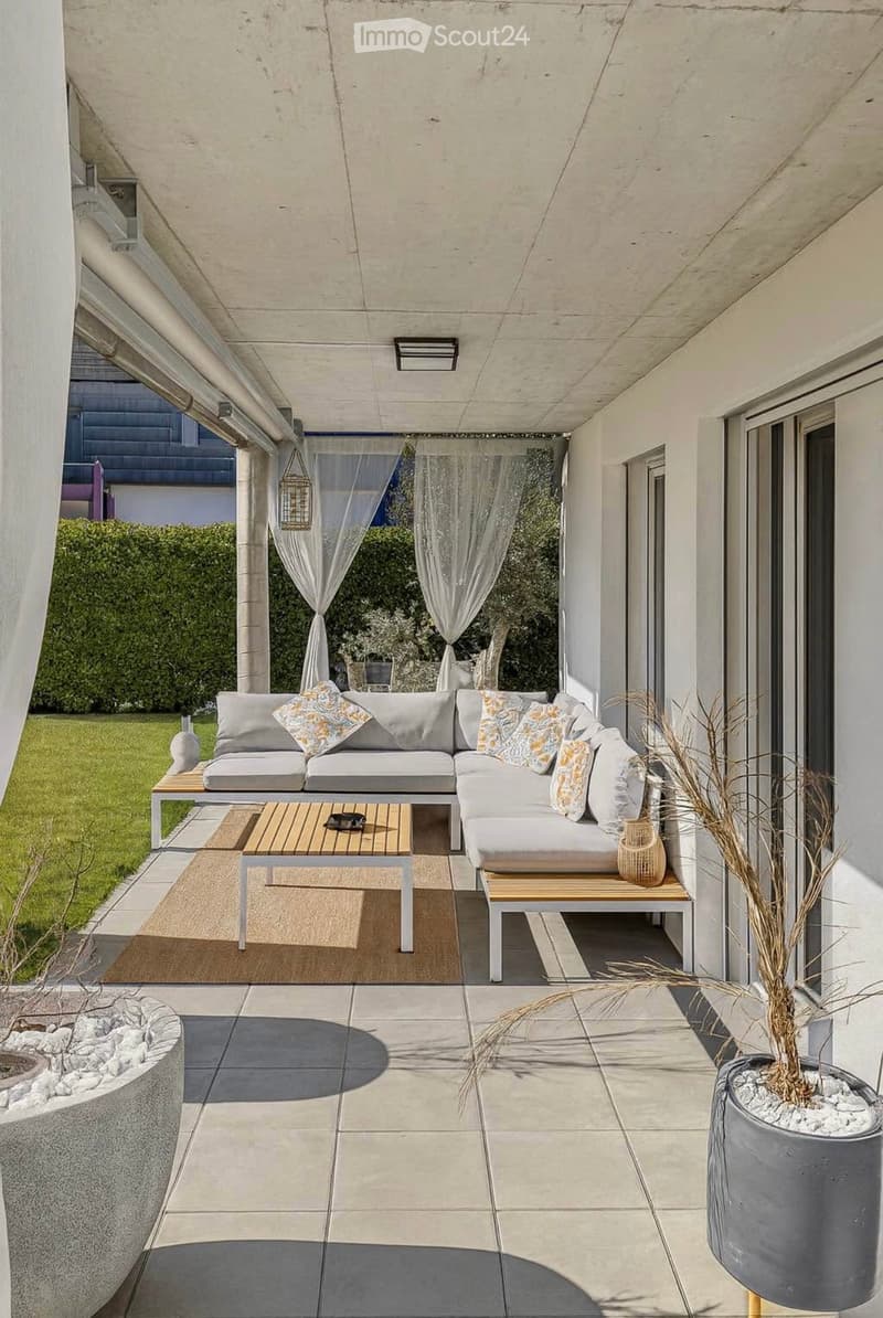 Modern outdoor patio with a grey sectional sofa, wooden coffee table, and decorative vases.