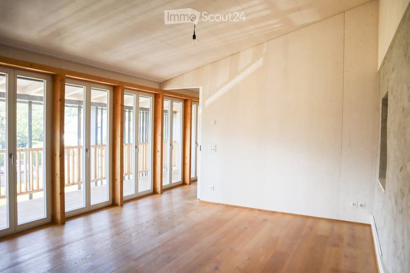 Empty room with wooden flooring, white walls, and large sliding glass doors leading to a balcony.