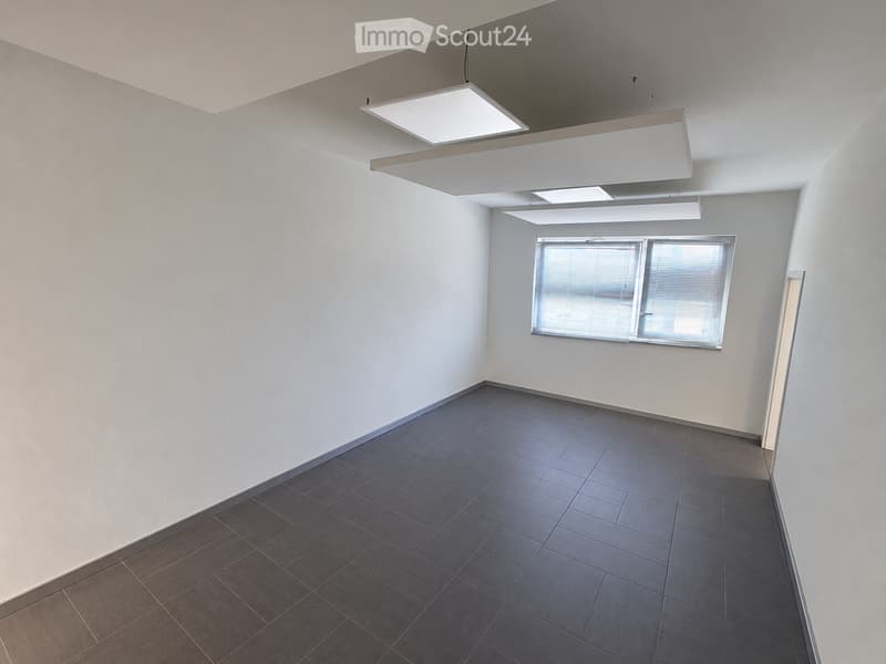 Empty room with white walls, dark tiled floor, large window with blinds, and modern ceiling lights.