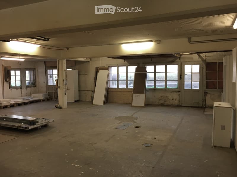 Empty room with bare walls, concrete floor, and large windows. No furniture or equipment present.