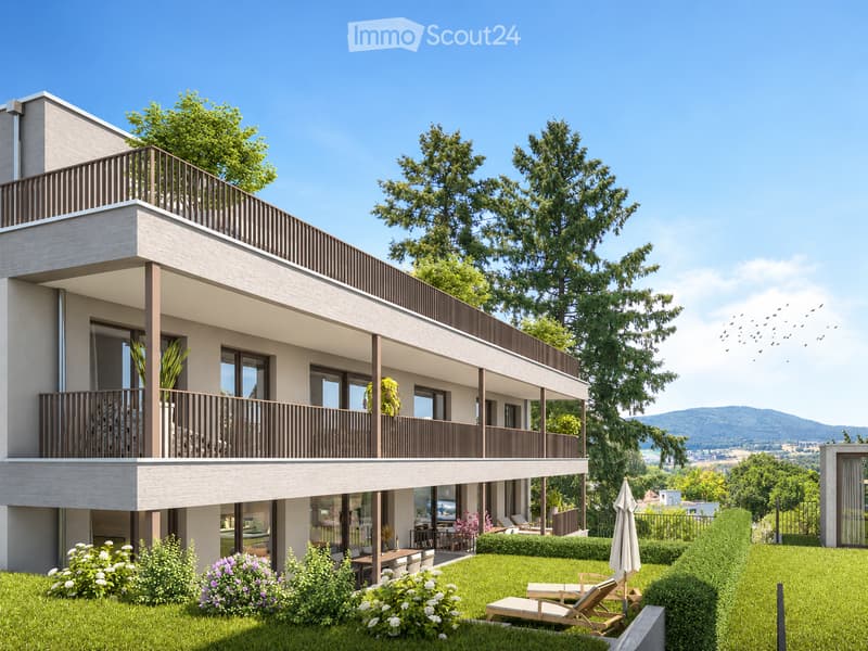Modern two-story building with balconies, large windows, and a well-maintained garden area with lounge chairs and an umbrella.