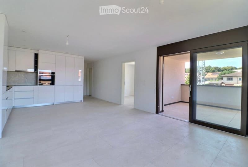 Empty room with tiled floor, white walls, and a sliding glass door leading to a balcony. The room has built-in kitchen cabinets and an oven on the left side.