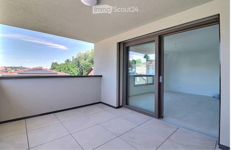 Balcony with tiled floor, large glass sliding doors, and a view of the surrounding area with trees and rooftops.
