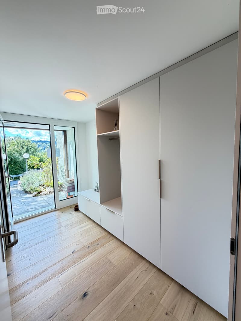 Empty room with light wooden flooring, white walls, built-in white cabinetry, and a large glass door leading to an outdoor area.