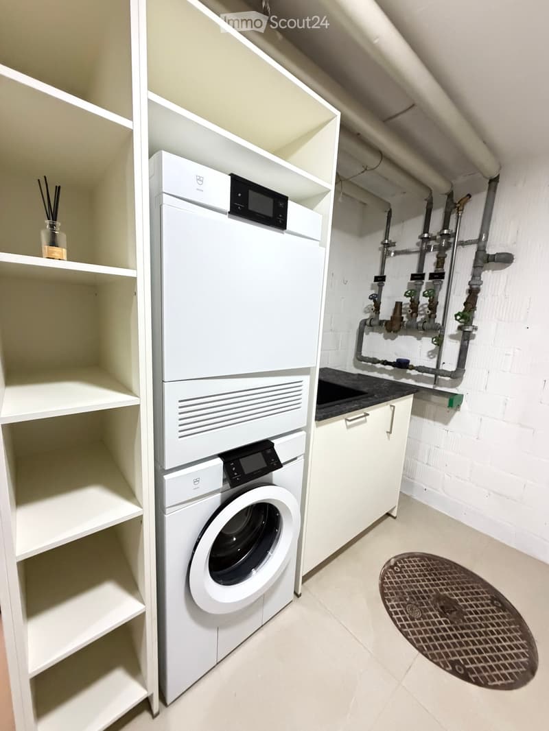 Modern bathroom with white washing machine and dishwasher, white cabinetry, and built-in shelving.