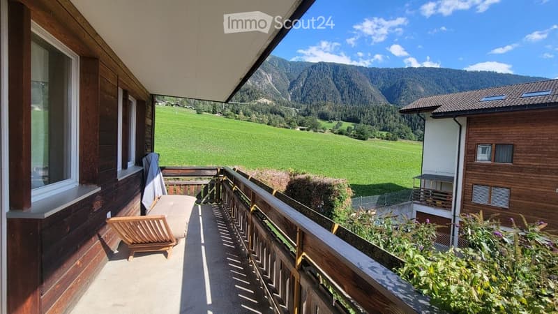 Balcony with wooden railing, lounge chair, and scenic mountain view.