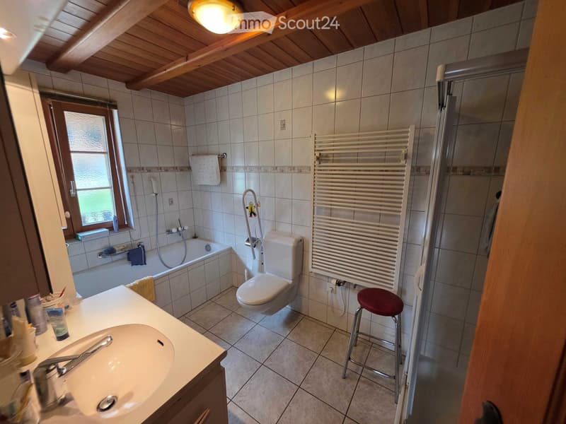 Bathroom with a sink, toilet, bathtub, shower, radiator, and a small window. Wooden ceiling and tiled walls.