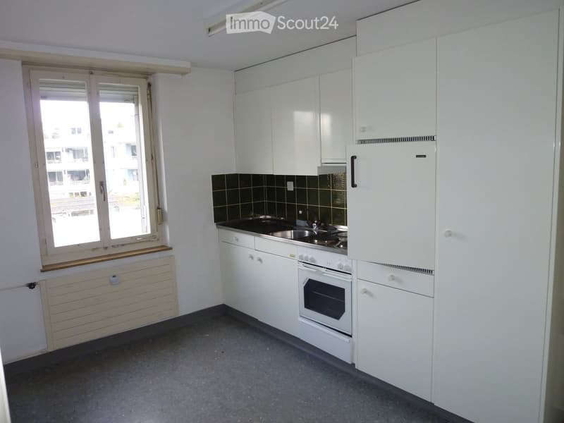 Modern kitchen with white cabinets, stainless steel appliances, and a window offering a view of the building exterior.
