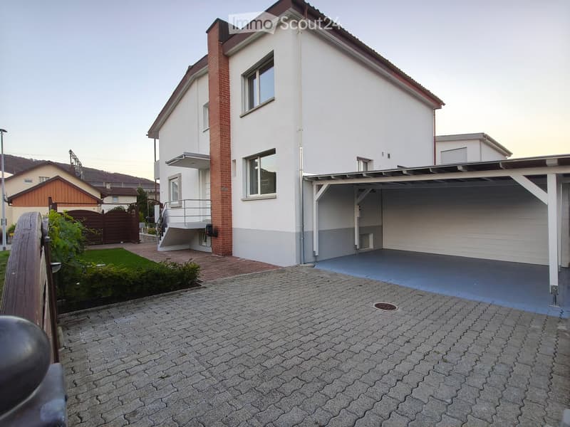 Two-story house with white walls, red brick chimney, garage, and small balcony on the upper floor.