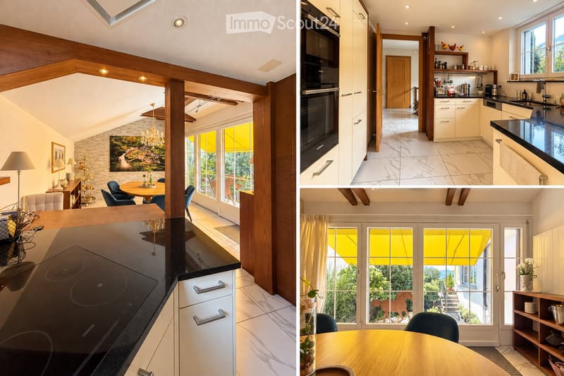 The image shows a modern, well-furnished living and dining area with a kitchen. The living area features a sofa, a dining table with chairs, a chandelier, and a floor lamp. The kitchen has white cabinets, an oven, a sink, and a countertop. Large windows p