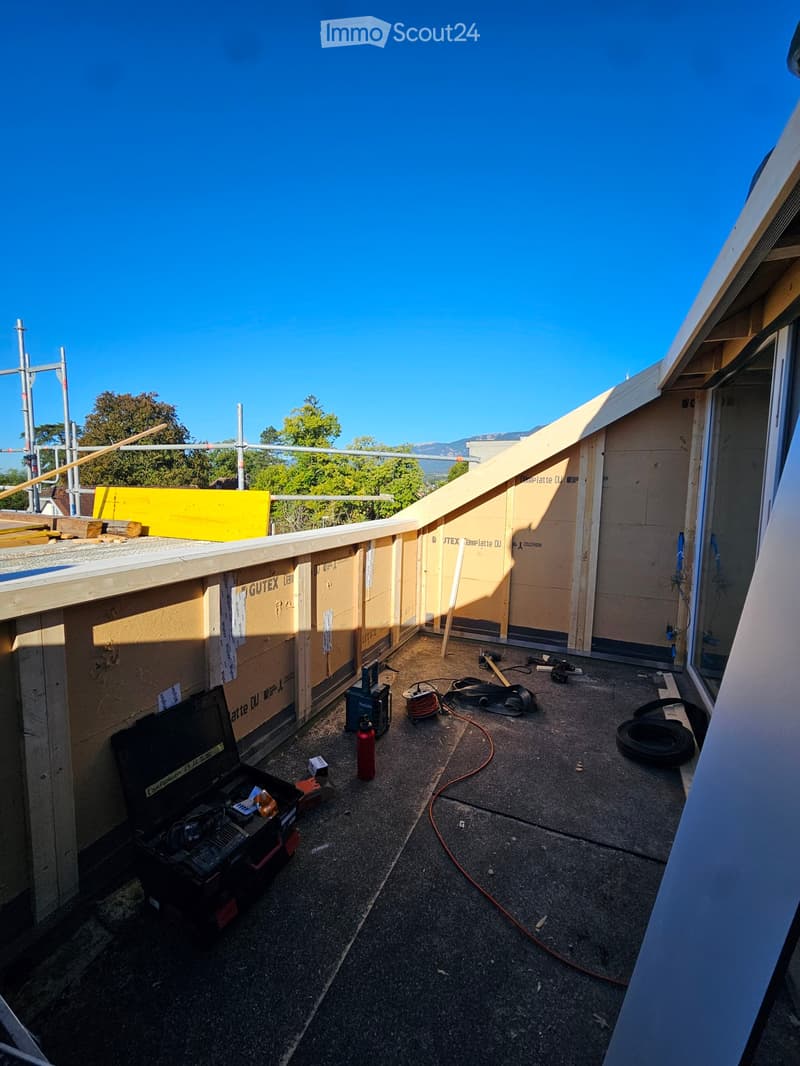 Roof terrace under construction with exposed wooden framing, tools, and materials scattered across the surface.