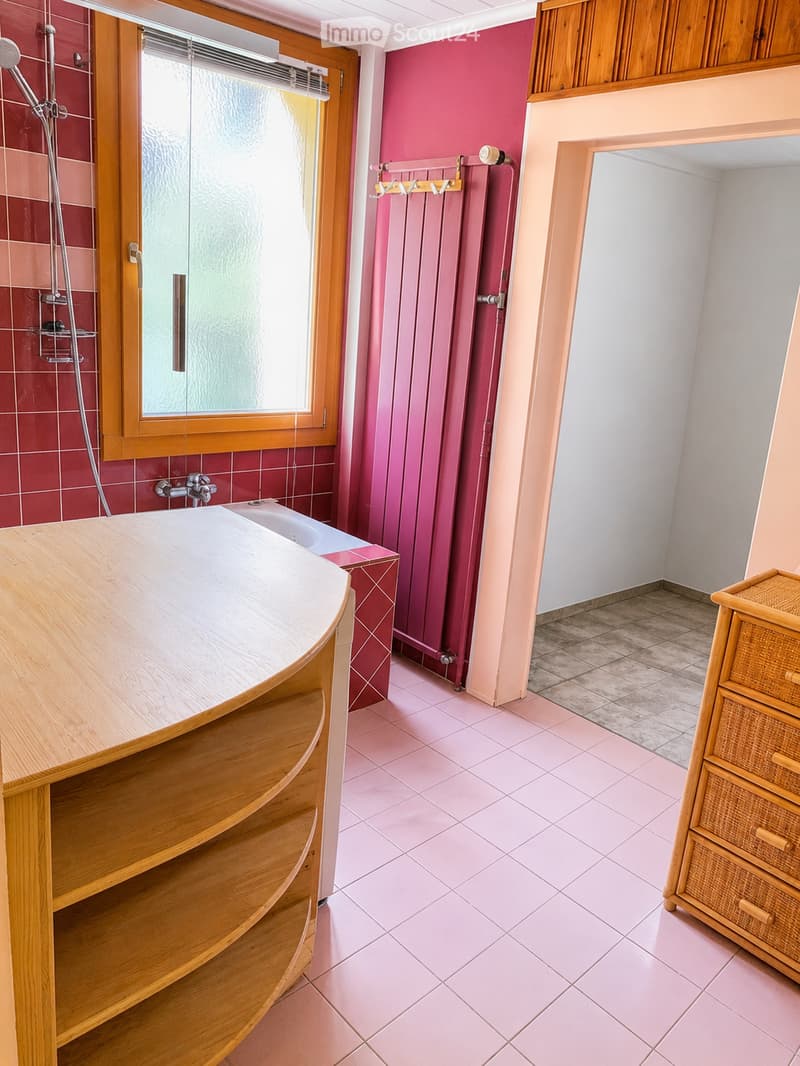 Bathroom with pink tiles, wooden vanity, wicker cabinet, shower stall, and radiator.