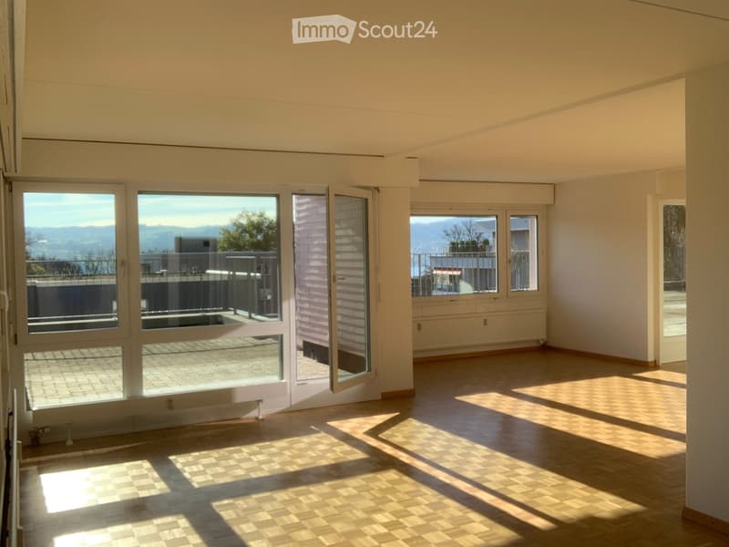 Empty room with wooden flooring, large windows, and a view of a balcony area. No furniture or equipment is present.