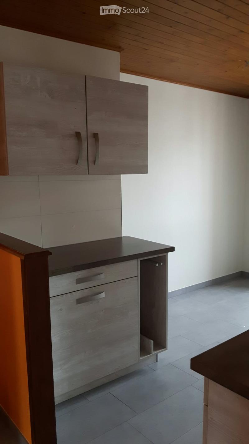 Modern kitchen with light grey cabinets, a dark countertop, and a wooden ceiling. The space is clean and well-lit with tiled flooring.