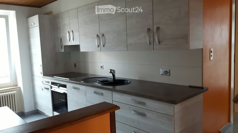 Modern kitchen with white cabinets, stainless steel appliances, and a dark countertop.