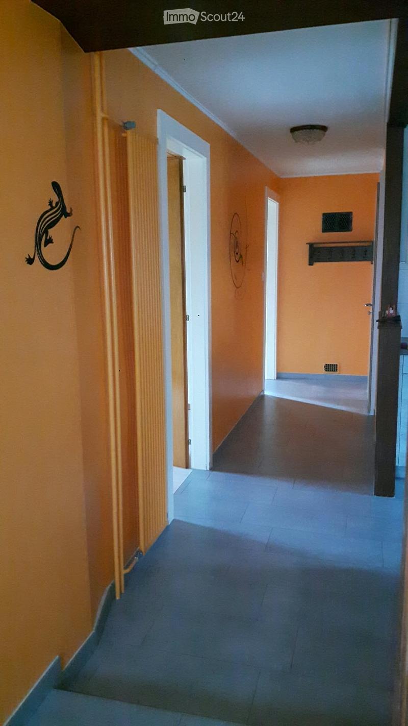 A narrow hallway with orange walls, tiled floor, and several doors leading to other rooms.