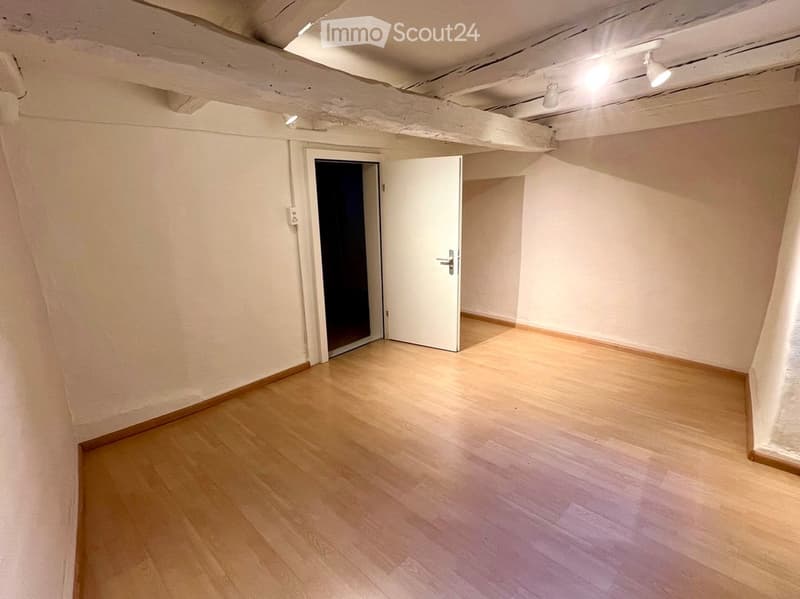 Empty room with wooden flooring, white walls, and two doors, one open and one closed.