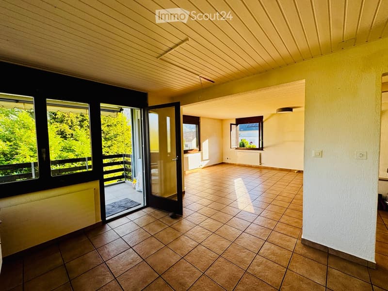 Empty room with tiled floor, large windows, and a sliding glass door leading to a balcony.