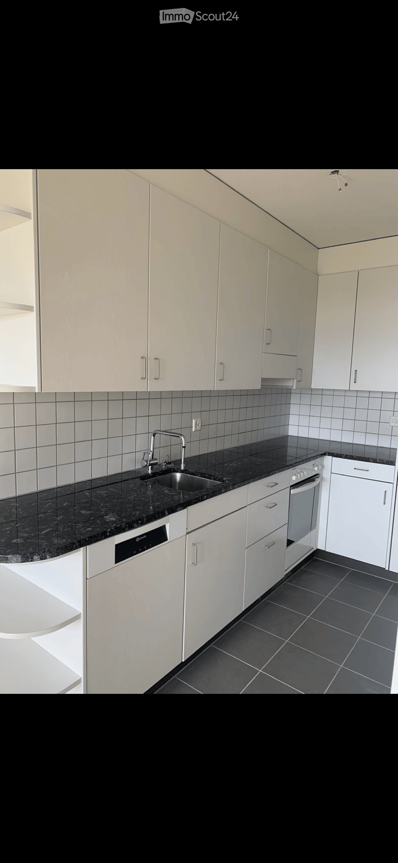 Modern kitchen with white cabinets, black granite countertop, stainless steel sink and faucet, built-in oven, and dishwasher.