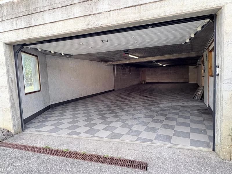 Underground garage with checkered tiled floor, concrete walls, and multiple doors leading to other areas.