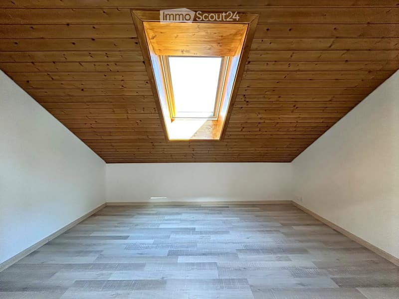 Empty room with wooden floor and white walls, featuring a skylight window in the ceiling.