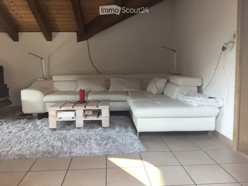 Modern living room with a white sectional sofa, wooden coffee table, floor lamp, and a shaggy rug on tiled flooring.