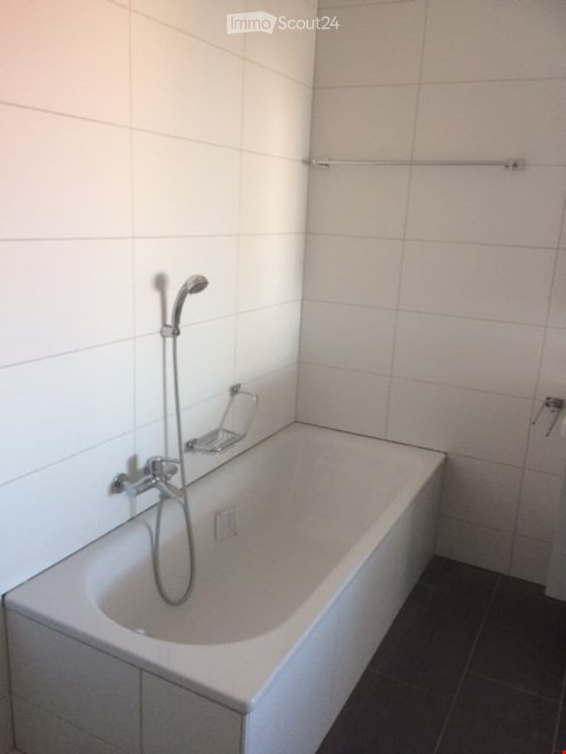 Modern bathroom with a white bathtub, showerhead, and chrome fixtures.